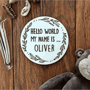A round wooden plaque with a hand-burnt inscription that reads, "Hello world, my name is Oliver."