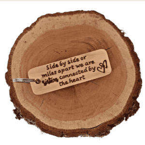 handmade wooden sycamore keyring with hand burnt text saying 'side by side or miles apart, we are sisters connected by heart