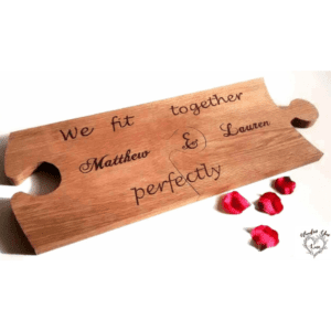 A solid oak 2-piece serving board in a unique jigsaw piece shape. The board features a rich, natural wood grain and smooth finish. It consists of two interlocking pieces that fit together perfectly, forming a complete puzzle shape. The board is ideal for serving appetizers, cheese, fruits, or other delicious treats. Its sturdy construction and elegant design make it a beautiful addition to any dining or entertaining space."