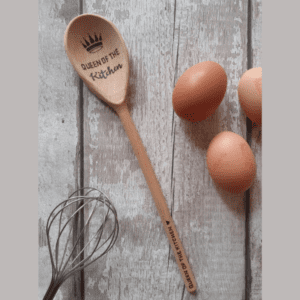 "A regal wooden spoon fit for the Queen of the kitchen. Crafted from fine hardwood, this spoon features a polished handle adorned with intricate carvings, reminiscent of a royal scepter. The spoon's broad, shallow bowl is perfectly suited for stirring and mixing culinary creations with grace and precision. A symbol of culinary authority, this wooden spoon is both functional and elegant, embodying the queen's mastery of the kitchen realm."
