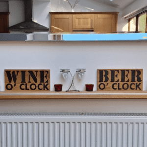 oak wood sign with hand burnt text saying 'beer o'clock' and 'wine o'clock'