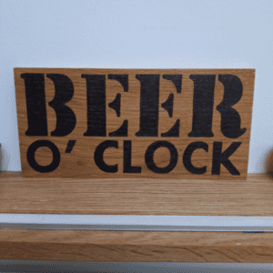 oak wood sign with hand burnt text saying 'beer o'clock'