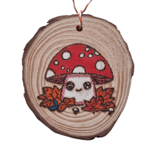 hand burnt rustic wood slice with a kawaii style mushroom in autumn leaves