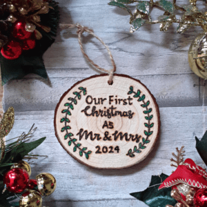 A charming rustic Christmas tree ornament, featuring a wooden slice that reads "Our First Christmas as Mr. and Mrs." The ornament is adorned with intricate hand burnt lettering and is jute hanging rope. The ornament exudes a cozy, nostalgic feel, perfect for commemorating the joyous occasion of a couple's first Christmas together as husband and wife in 2024