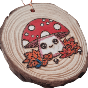 hand burnt rustic wood slice with a kawaii style mushroom in autumn leaves