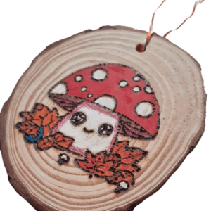 hand burnt rustic wood slice with a kawaii style mushroom in autumn leaves