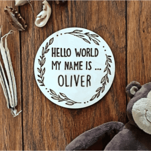 A round wooden plaque with a hand-burnt inscription that reads, "Hello world, my name is Oliver."