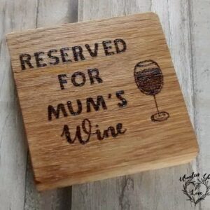 A square oak coaster featuring hand-burnt text that reads 'reserved for mums wine.' The coaster showcases a natural wood grain pattern, with a rich brown color and a smooth, polished surface. The text is carefully engraved with intricate detail, adding a touch of whimsy to the design. The coaster serves as a functional and decorative piece, perfect for holding a glass of wine while adding a playful and humorous element to any setting."