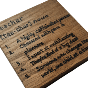 A square handmade wooden coaster made of oak, describing a teacher. The coaster features a hand-burnt inscription in a charming, rustic font. The wood's natural grain and texture are visible, adding to its artisanal and heartfelt appearance.