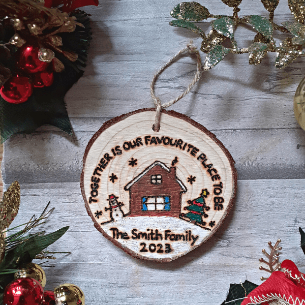 A festive Christmas tree ornament with a rustic design. The ornament features a charming house motif and a heartwarming message that reads, "Together is our favorite place to be - 2023.