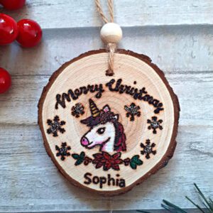 handmade wooden unicorn christmas ornament on a wood slice. Unicorn head and personalised with a name and a touch of glitter