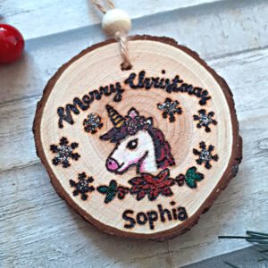 handmade wooden unicorn christmas ornament on a wood slice. Unicorn head and personalised with a name and a touch of glitter