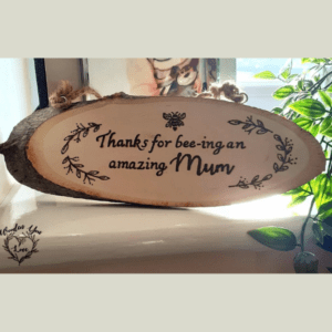 A handcrafted, burnt rustic oval plaque with a heartfelt message that reads, "Thank you for bee-ing an amazing mum." The plaque features a charming design, showcasing the word "bee-ing" cleverly, with a whimsical bee motif. The burnt edges and natural wood grain add a touch of rustic charm to the overall aesthetic.