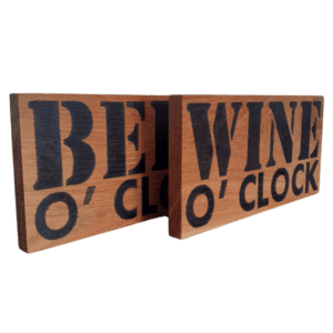 oak wood sign with hand burnt text saying 'beer o'clock' and 'wine o'clock'