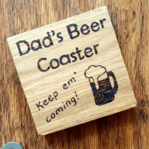 A solid oak coaster designed for a beer. The coaster is square in shape and made from high-quality oak wood. It features a smooth surface with a natural wood grain pattern. The coaster is sturdy and durable, providing a reliable surface to rest a beer glass upon. Its neutral brown color complements any decor and adds a touch of rustic elegance to the table. A practical and stylish accessory for beer enthusiasts and those who appreciate artisanal craftsmanship."