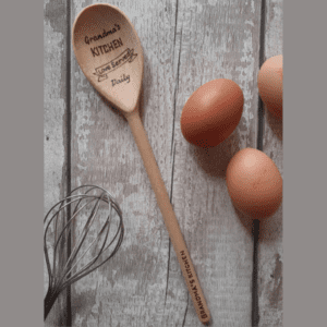 An intricately carved wooden spoon, lovingly crafted for Grandma, symbolizing the cherished bond shared through generations. Its smooth texture and warm hues evoke comfort and nostalgia. A timeless utensil, this spoon represents the daily act of love, as delicious meals are prepared and served with care. Its handle bears the engraved words 'Love is served daily,' reminding us of the enduring affection that permeates every mealtime shared with Grandma."