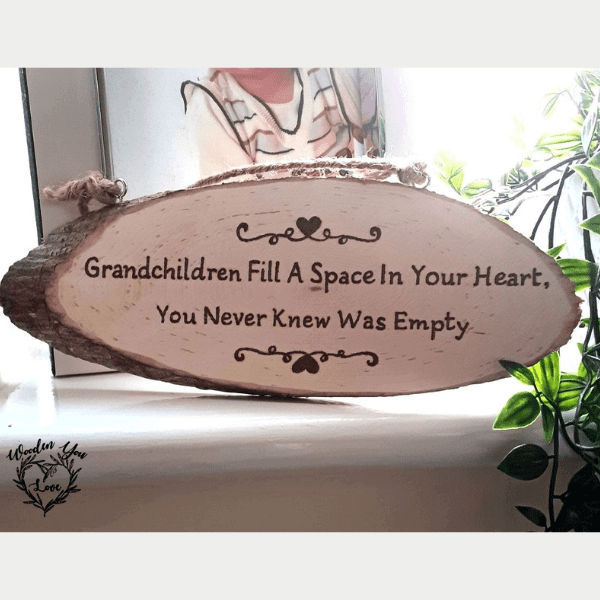 A hand-burnt rustic oval plaque featuring the heartfelt phrase, "Grandchildren fill a space in your heart, you never knew were empty."