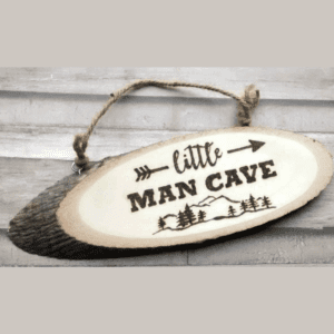A hanging log slice with a hand-burnt mountain design and the words "Little Man Cave."