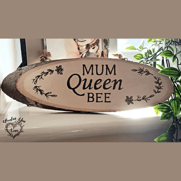 A hand-burnt rustic oval plaque featuring the phrase "Mum Queen Bee" with an intricately designed bee motif.