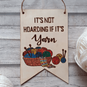 A hand-burnt sign displaying the phrase "It's not hoarding if it's yarn."